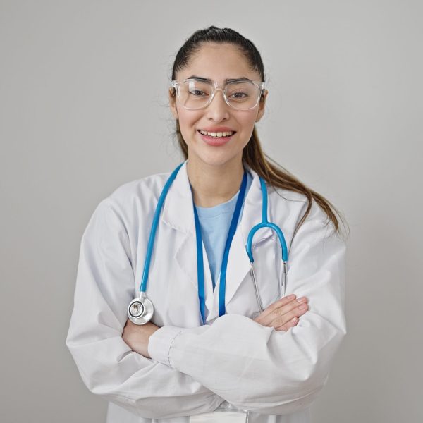 Young beautiful hispanic woman doctor smiling confident standing with arms crossed gesture over isolated white background